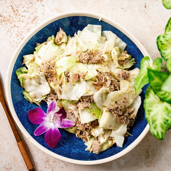 Hawaiian cabbage and tuna dish in a blue bowl, garnished with a purple orchid.