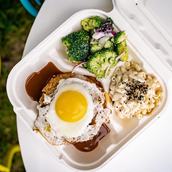Hawaiian Loco Moco with a fried egg, gravy, rice, macaroni salad, and broccoli in a takeout container.