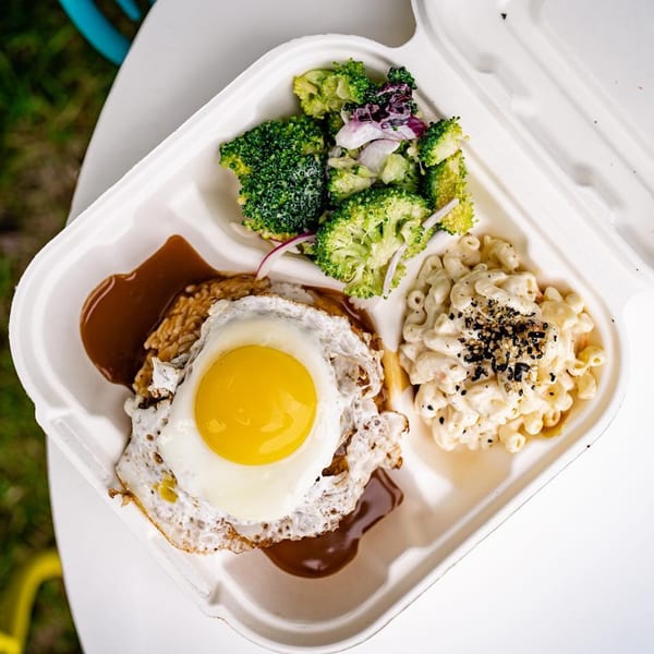 Hawaiian Loco Moco with a fried egg, gravy, rice, macaroni salad, and broccoli in a takeout container.