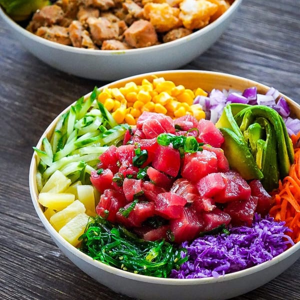 Close-up of a colorful Hawaiian poké bowl with tuna, avocado, corn, and various vegetables.
